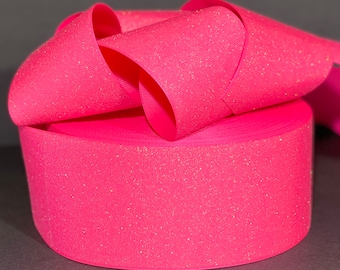 May include: A roll of pink glitter ribbon. The ribbon is a light pink color with a fine glitter finish.