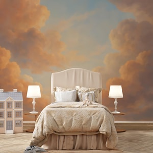 Pode incluir: Uma cena de quarto com uma cama com cabeceira e roupa de cama creme. Duas lâmpadas brancas ladeiam a cama. Uma casa de bonecas está à esquerda. O fundo é um mural de um céu ao pôr do sol com nuvens laranja e azuis.