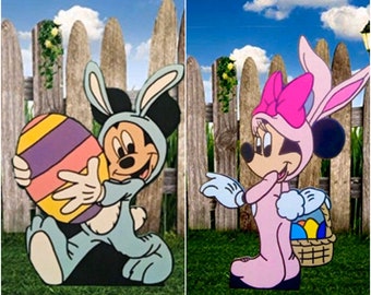 May include: Two Easter-themed cardboard cutouts of Mickey Mouse and Minnie Mouse. Mickey is wearing a blue bunny costume and holding a large, colorful Easter egg. Minnie is wearing a pink bunny costume and holding a basket of colorful Easter eggs.