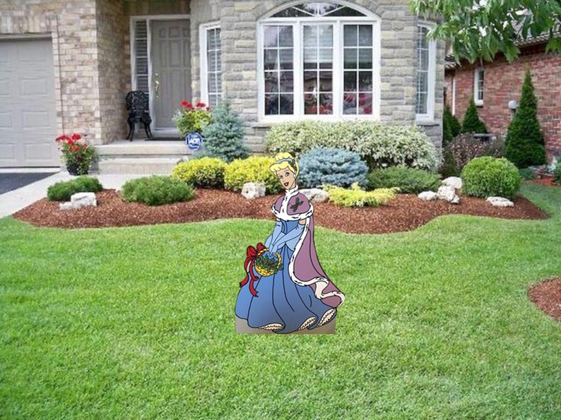 May include: A cartoon illustration of Cinderella in a blue dress and purple cape holding a basket of flowers. The illustration is standing on a green lawn in front of a house.
