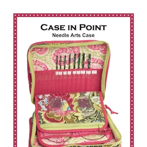 May include: A pink and green fabric needle arts case with multiple pockets and compartments for storing needles, hooks, and other supplies. The case has a zipper closure and a removable shoulder strap. The text "CASE IN POINT" and "Needle Arts Case" is printed on the front of the case. The text "Patterns by Annie", "www.ByAnnie.com", and "435-674-9816" is printed on the bottom of the case.