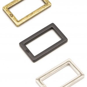 May include: Three metal rectangular rings in gold, black, and silver.