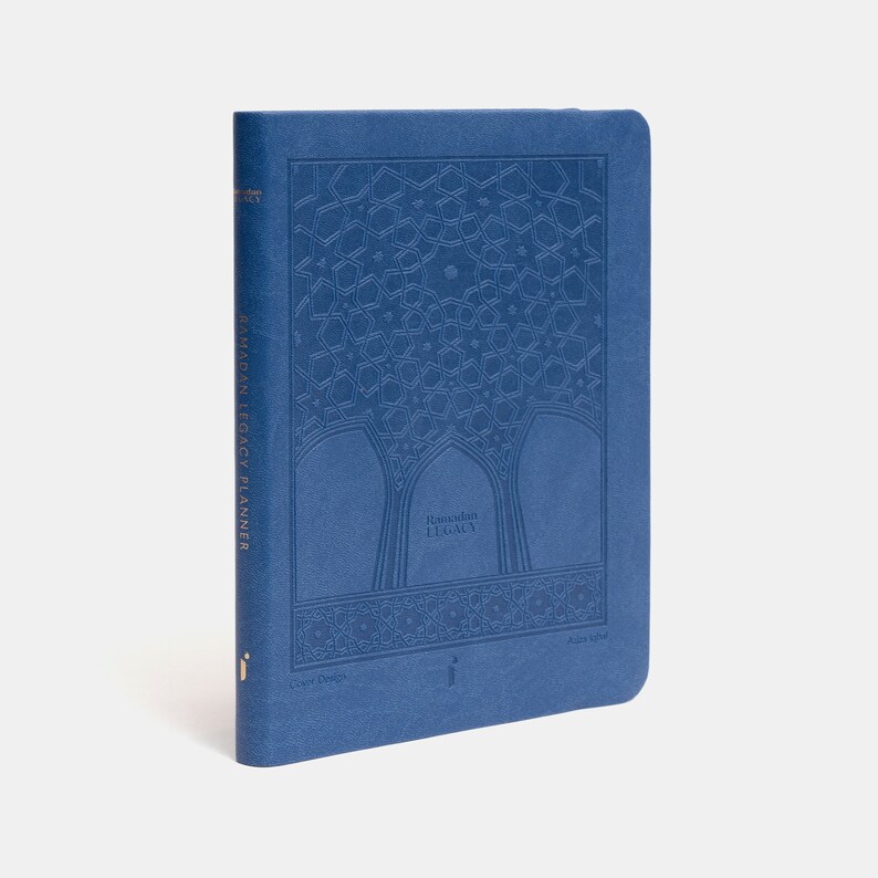 May include: A blue Ramadan Legacy Planner with a gold embossed design of an Islamic archway and the text "Ramadan Legacy" on the front cover.