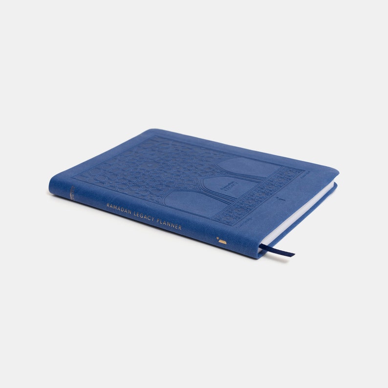 May include: A blue leather-bound journal with a gold embossed design of a mosque and the text "Ramadan Legacy Planner".
