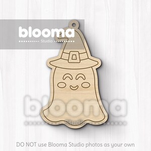 May include: A wooden Halloween-themed cutout of a ghost wearing a witch hat. The ghost has a smiling face with oval eyes and a curved mouth. The hat has a buckle. The cutout has a hole at the top for hanging. The text "blooma Studio" is visible.