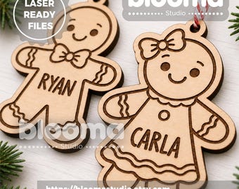 May include: Two light-colored wooden gingerbread person ornaments with red and white twine hangers. One ornament features a bowtie and the name RYAN, while the other features a hair bow and the name CARLA. Both have etched details and smiling faces.