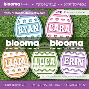May include: Five colorful Easter egg cut files with names: Ryan, Cara, Liam, Luca, and Erin. Each egg is a different pastel color and has a unique decorative design. The eggs are set against a green grass background.