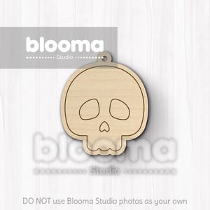 May include: A wooden skull-shaped cutout with a small hole at the top for hanging. The skull has eye and nose openings and a detailed jawline. The cutout is made of light-colored wood and is suitable for crafting or decoration.