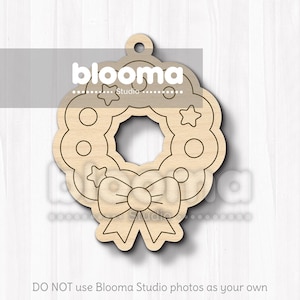 May include: A wooden Christmas wreath ornament with a bow and star details. The ornament has a hole at the top for hanging. The text "blooma Studio" is visible on the top of the ornament. The bottom of the image has the text "DO NOT use Blooma Studio photos as your own".