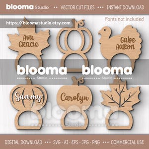 Puede incluir: Tarjeteros de madera con temática otoñal en forma de hoja, calabaza y pavo. Cada uno tiene un nombre grabado. También se ve el texto "blooma Studio" y "Instant Download".