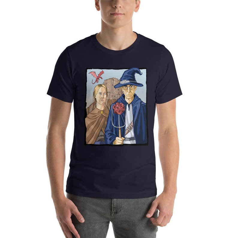 May include: A navy blue t-shirt with a graphic of a wizard and a woman standing in front of a castle. A red dragon flies above them. The wizard is holding a staff with a red twenty-sided die on top.