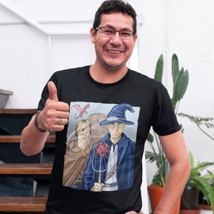 May include: A black t-shirt with a graphic of a wizard and a woman holding a pitchfork and a 20-sided die. The graphic is a parody of the famous painting "American Gothic".