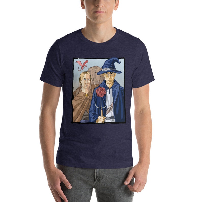 May include: A navy blue t-shirt with a graphic of a wizard and a woman standing in front of a castle. A red dragon flies above them. The wizard is holding a staff with a red dice on top.