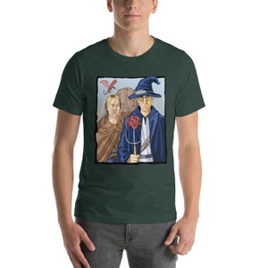 May include: A green t-shirt with a graphic of a wizard and a woman standing in front of a castle. A red dragon flies overhead. The wizard is holding a staff with a red and white dice on top.
