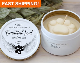 May include: White candle tin with a paw print design on the top. The lid has a black and white image of a paw print with angel wings and the text "A light remains where a beautiful soul has passed". The candle tin also has the text "In loving memory of Murphey".