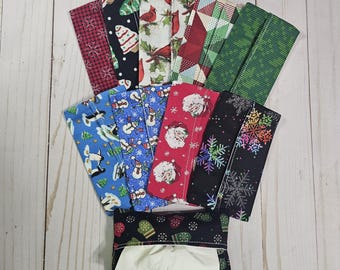 May include: A set of 10 Christmas-themed fabric tissue holders. The holders are made of different fabrics with various holiday patterns, including penguins, snowmen, snowflakes, and Santa Claus. The holders are arranged in a fan shape, with a white tissue box in the centre.