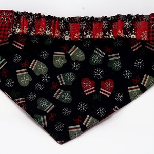 May include: A black bandana with a red and white plaid border. The bandana features a repeating pattern of green and red mittens and white snowflakes.