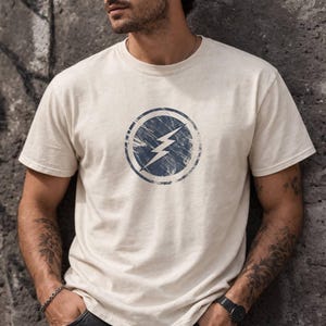 Distressed lightning bolt graphic t-shirt with circular emblem printed on ringer and classic cotton tees in multiple color options
