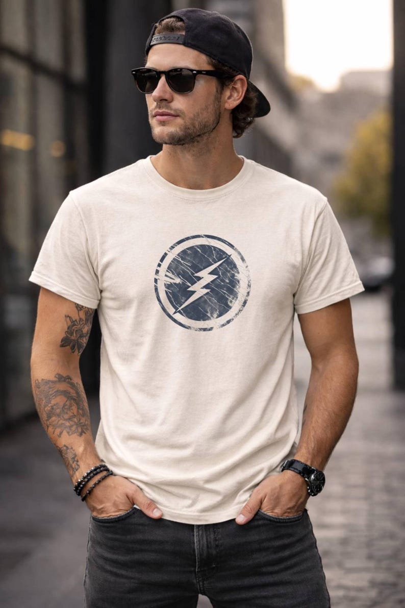 Distressed lightning bolt graphic t-shirt with circular emblem printed on ringer and classic cotton tees in multiple color options