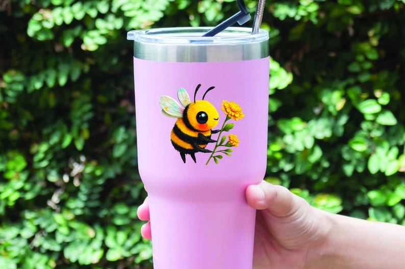Adorable die-cut vinyl design of a fuzzy yellow honeybee holding a bright yellow flower. Shown as a fridge magnet displayed on a stainless steel refrigerator. This design is also available as a waterproof transparent sticker in five sizes. Ideal for decorating laptops, journals, water bottles, fridges, and more. Suitable for indoor and outdoor use.