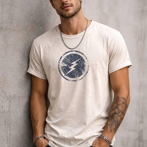 Distressed lightning bolt graphic t-shirt with circular emblem printed on ringer and classic cotton tees in multiple color options