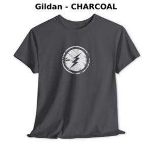 Distressed lightning bolt graphic t-shirt with circular emblem printed on ringer and classic cotton tees in multiple color options