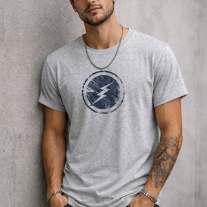 Distressed lightning bolt graphic t-shirt with circular emblem printed on ringer and classic cotton tees in multiple color options