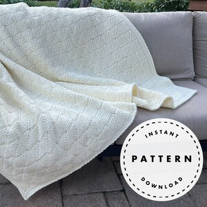 Puede incluir: Manta de punto color crema con un patrón de diamantes sobre un sofá gris para exteriores. La manta es gruesa y texturizada, con detalles de puntadas visibles. Un gráfico circular con las palabras "INSTANT PATTERN DOWNLOAD" está en la esquina inferior derecha.