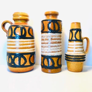 May include: Three ceramic vases with a brown, white and black geometric pattern. The vases are of different sizes and shapes.