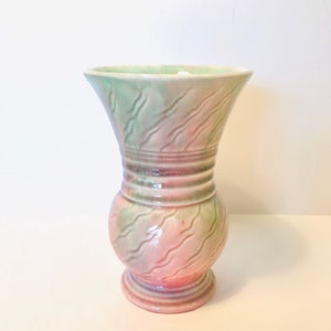 May include: A vintage ceramic vase with a green and pink swirl design. The vase has a wide mouth and a narrow base.
