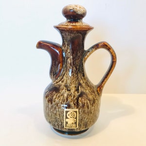 May include: A brown and white ceramic jug with a gold label that says "Fosters South West".