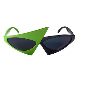 May include: Geometric sunglasses with a striking design. One lens is bright green, the other is black. The frames have a sharp, angular shape, and the lenses are dark, providing a bold, modern look. The sunglasses are set against a white background.