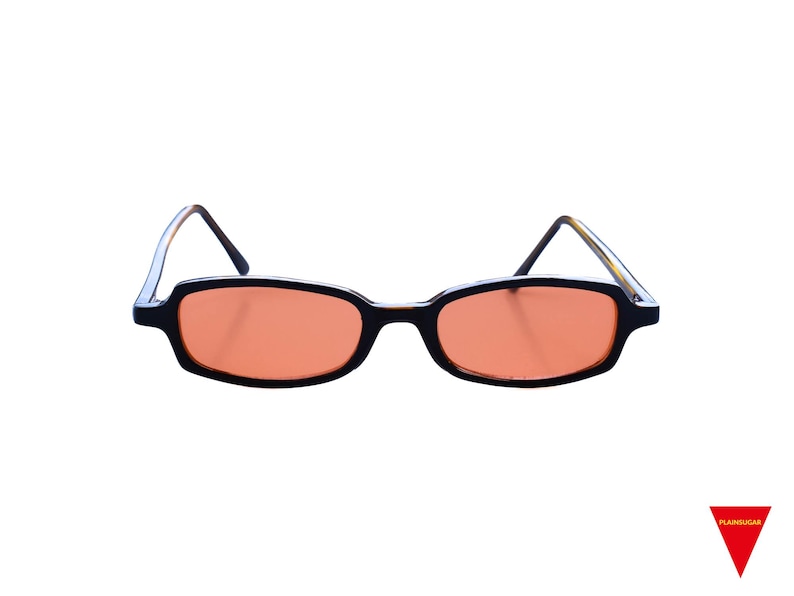May include: Rectangular sunglasses featuring black frames and orange-tinted lenses. The temples are thin and dark, extending from the outer corners of the frames. A small red triangle logo with the text "PLAINSUGAR" is visible in the bottom right corner.