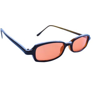 May include: Rectangular sunglasses featuring dark brown frames and orange-tinted lenses. The glasses have thin, matching brown temples and a bridge connecting the two lenses. A small red triangular logo with the text "PLAINSUGAR" is in the corner.