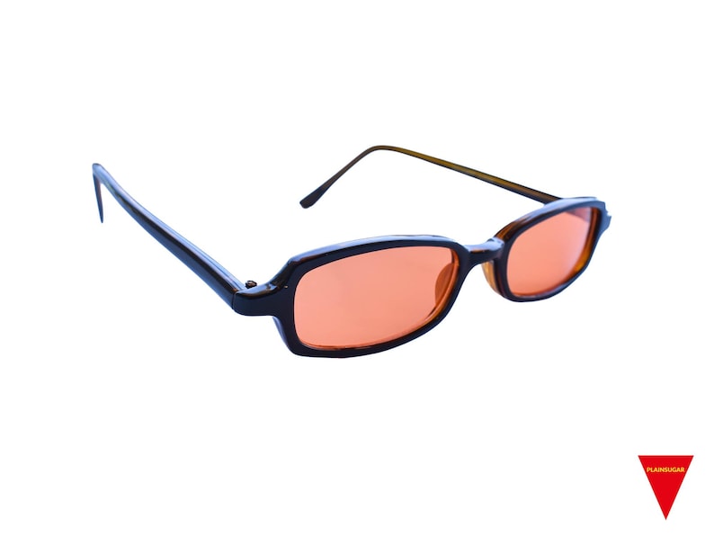 May include: Rectangular sunglasses featuring dark brown frames and orange-tinted lenses. The glasses have thin, matching brown temples and a bridge connecting the two lenses. A small red triangular logo with the text "PLAINSUGAR" is in the corner.