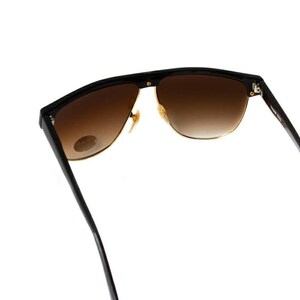 May include: Black sunglasses with brown gradient lenses and gold accents. The sunglasses have a wraparound design and are made of a lightweight material.