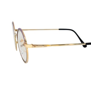 May include: Gold-tone round eyeglasses with purple accents on the frame and black temple tips.