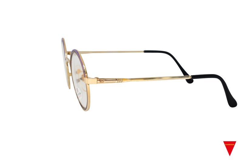 May include: Gold-tone round eyeglasses with purple accents on the frame and black temple tips.