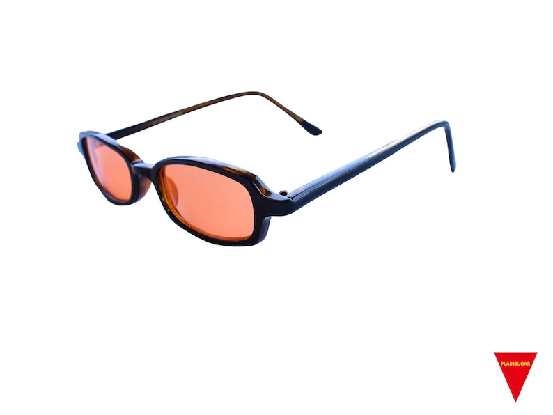 May include: Oval-shaped glasses featuring dark brown tortoiseshell frames and vibrant orange-tinted lenses. The eyewear includes thin, matching brown temples that extend from the sides, providing a classic look with a distinctively colored lens.