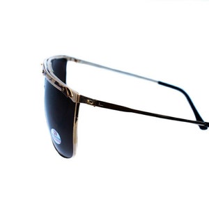 May include: A pair of gold-rimmed sunglasses with dark lenses. The sunglasses have a thin metal frame and black plastic arms.