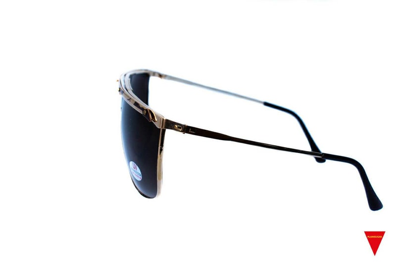 May include: A pair of gold-rimmed sunglasses with dark lenses. The sunglasses have a thin metal frame and black plastic arms.
