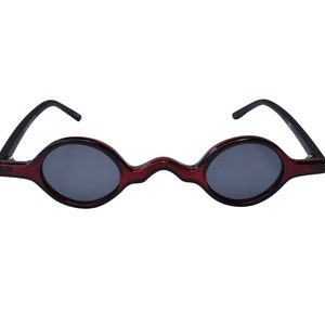 Puede incluir: Gafas de sol redondas rojas y negras con un puente ondulado único.