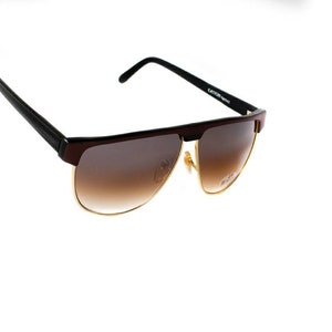 May include: Brown and black sunglasses with gold accents. The lenses are brown gradient.