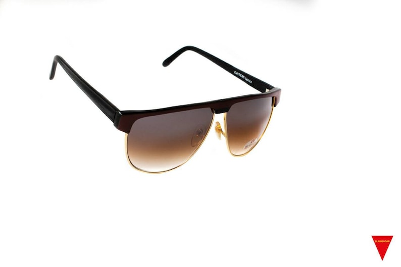 May include: Brown and black sunglasses with gold accents. The lenses are brown gradient.