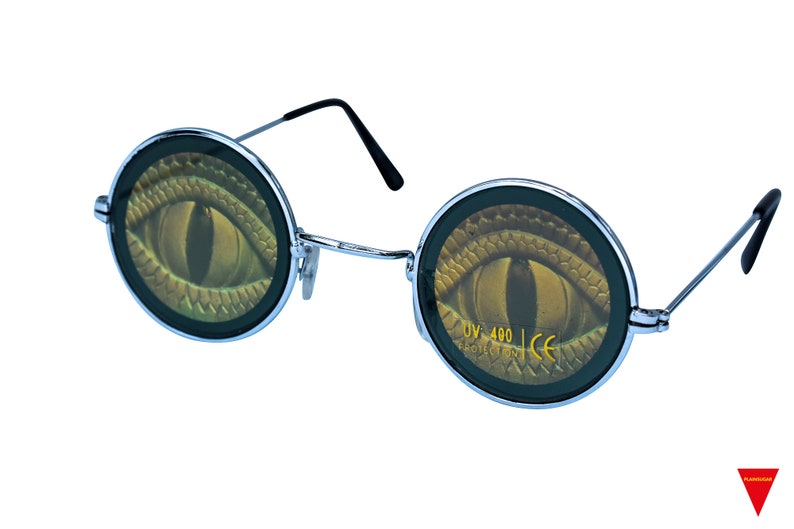 May include: Round sunglasses with a silver frame and black arms. The lenses have a graphic of a green snake eye with gold scales. The text "UV 400 PROTECTED CE" is printed on the right lens.
