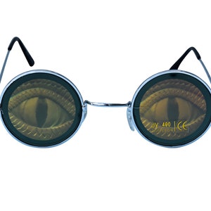May include: Round silver-framed sunglasses with a black eye design on the lenses. The lenses have the text "UV 400 PROTECTION CE" printed on them.