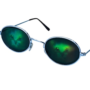 Puede incluir: Gafas de sol redondas con montura plateada y lentes de espejo verde. El reflejo en las lentes muestra una imagen verde borrosa de un gato.