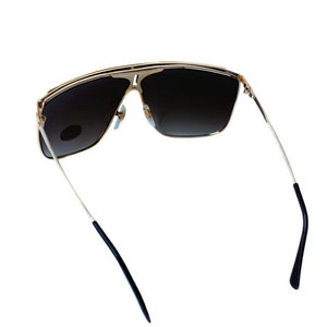 May include: Gold-tone sunglasses with dark brown lenses and black arms. The sunglasses have a square shape and a sleek design.