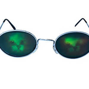 Puede incluir: Gafas de sol redondas con montura plateada y lentes espejados verdes. Los lentes reflejan una imagen borrosa de una cara.