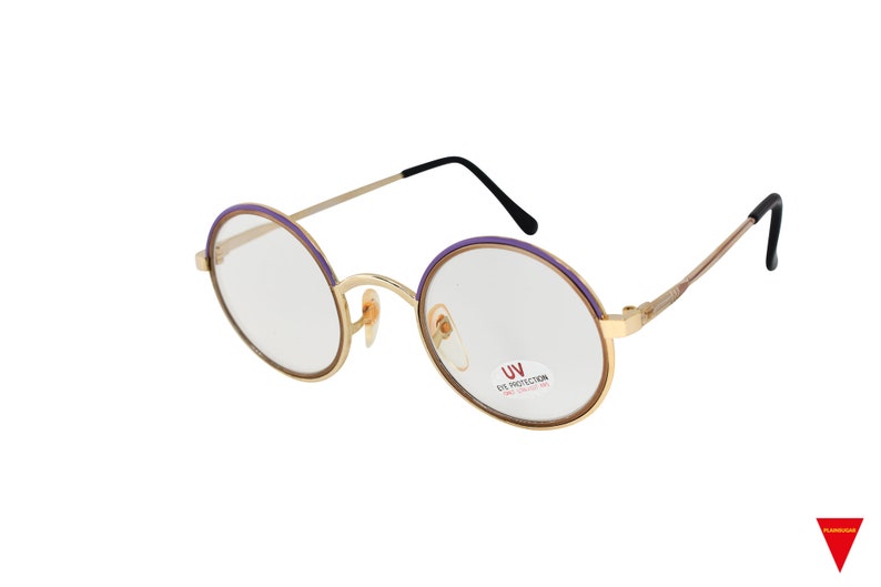 May include: Gold-rimmed round glasses with purple accents and clear lenses. The glasses have a UV eye protection label on the right lens.